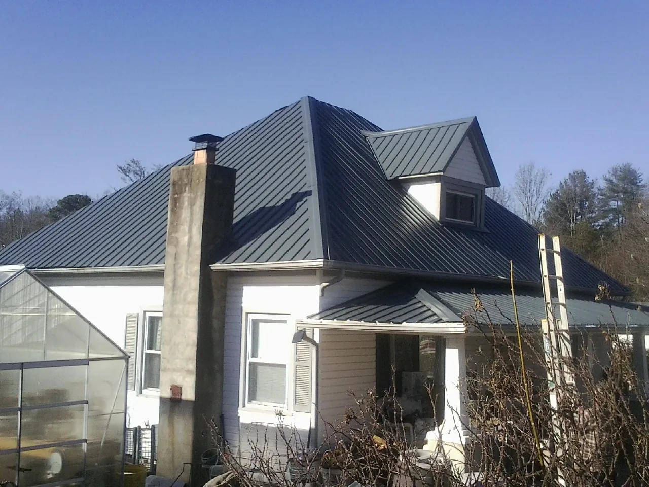 Dark blue standing seam metal roof on a white farmhouse with dormer — Slate & Tile Roof Repair by Roofing Brothers in Festus