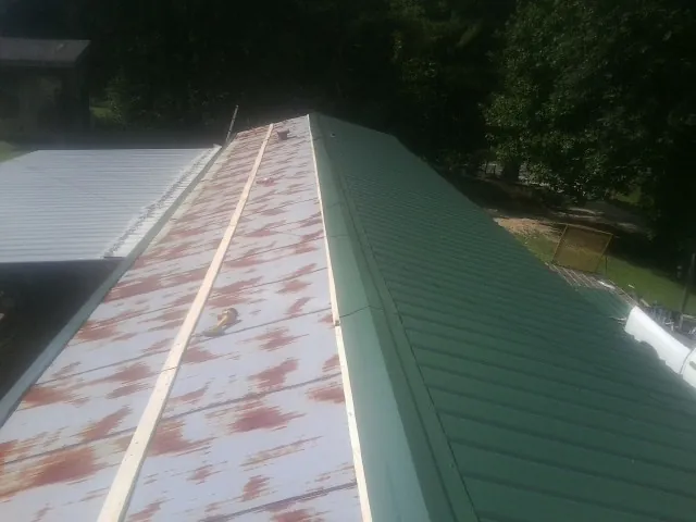 Old rusted panels beside newly installed green metal roofing — Wind Damage Roof Repair by Roofing Brothers in Festus