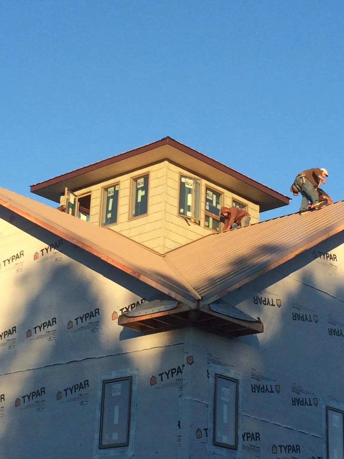 Roofers working around a rooftop cupola on a new metal roof at sunset — Roof Waterproofing in Festus by Roofing Brothers